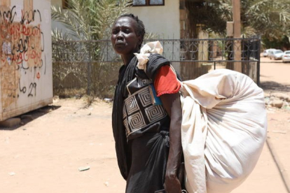 Una mujer sudanesa lleva sus pertenencias en una calle de Jartum, Sudán, tras el estallido del conflicto armado. STRINGER