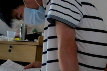Li Haiqing, de 26 años, leyendo el prospecto farmacéutico de uno de los medicamentos que debe tomar a causa de su enfermedad.
