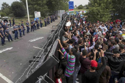 Refugiados sirios ante la valla fronteriza de Hungría.
