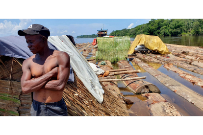 Un trabajador sobre troncos de madera remolcados río Congo abajo, con destino en la capital Kinshasa. MANUEL FÉLIX