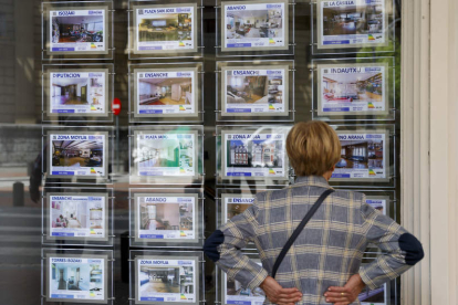 Una mujer mira los precios de los pisos en el escaparate de una inmobiliaria. LUIS TEJIDO