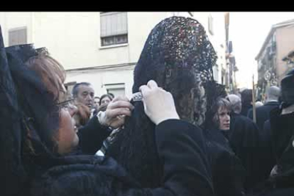 Las manolas, tradicionales mujeres vestidas de negro que acompañan las procesiones, se dan los últimos retoques antes de salir a recorrer las calles de León.