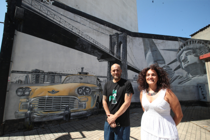 Asier vera posa junto a la arquitecta Belén Cuesta frente al primer mural que pintó en Ponferrada en el año 2014; una estampa de Nueva York que recuperó un rincón degradado de la calle San Fructuoso. L. DE LA MATA