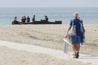 Una pareja se dirige a la playa mientras la Guardia Civil inspecciona el cadáver del niño. QUIQUE GARCÍA