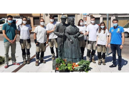 Los representantes municipales con los alumnos del taller junto a la escultura de los hortelanos. DL