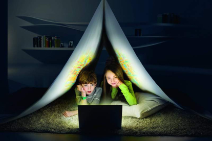 Un niño y una niña miran una pantalla de un ordenador en su habitación. DL