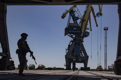 Un militar ruso vigila la carga de cereal en un puerto de Ucrania. SERGEI ILNITSKY