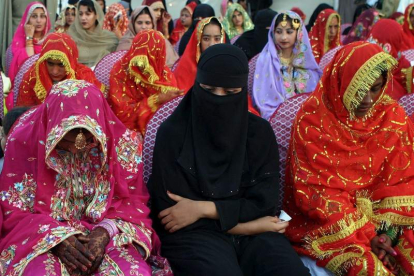 Mujeres paquistaníes vestidas con trajes de novia tradicionales participan en una boda en masa.