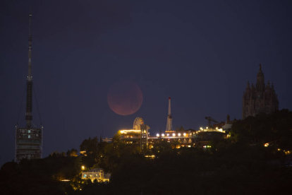 Vista del eclipse total de Luna tras el parque de atracciones del Tibidabo, la madrugada de este lunes. EFE/MARTA PÉREZ