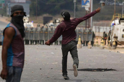 Un manifestante lanza una piedra contra policías venezolanos en la frontera con Brasil, este domingo. Un manifestante lanza una piedra contra policías venezolanos en la frontera con Brasil, este domingo.