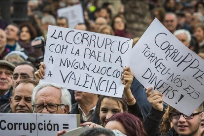 Asistentes a la manifestación contra la corrupción celebrada este domingo en Valencia portan carteles contra el PP y los casos que han afectado a esta comunidad.