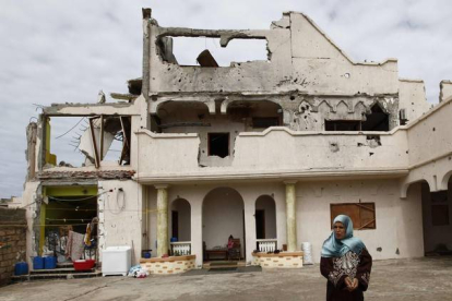 Una mujer permanece junto a su casa, parcialmente destruida por los bombardeos en Sirte.