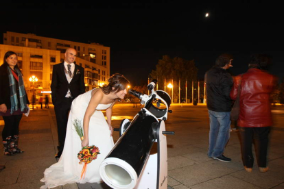 Una novia se acerca a observar la luna a través del telescopio de la Asociación de Astronomía.