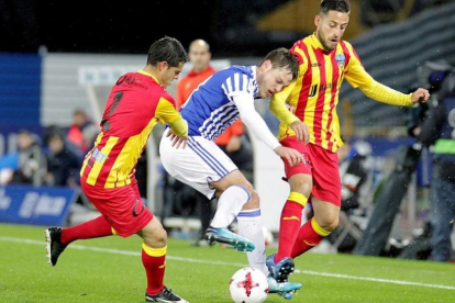 Bautista, de la Real, pelea un balón entre dos jugadores del Lleida.