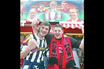 Dos aficionados de la Juventus y el Milan ante una pintura con las grandes leyendas del Machester Unites.