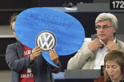 Una europarlamentaria alemana muestra un cartel en el que se lee "La austeridad es tóxica" y un logopito de la compañía Volkswagen durante la intervención de Angel Merkel en el Parlamento Europeo, ayer