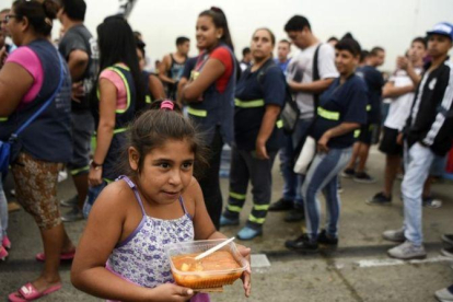 Una niña lleva su ración de comida servida durante una protesta social en Buenos Aires contra la pobreza, el 15 de marzo.
