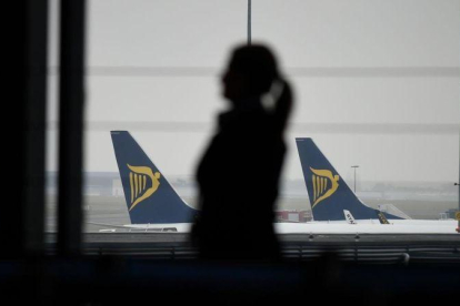 Una pasajera camina por el aeropuerto de Charleroi, en Bélgica, ante varios aviones de Ryanair