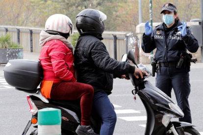 Una agente de la Policía Local de Valencia pregunta a dos personas que circulan en moto. JUAN CARLOS CÁRDENAS