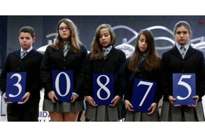 Los niños del Colegio San Ildefonso de Madrid posan con el número ganador del primer premio del sorteo del Niño.