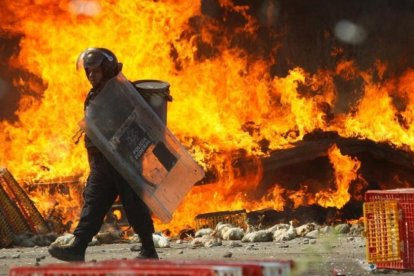 Un policía pasa frente a un camión en llamas durante las protestas contra la reforma educativa en Oaxaca.