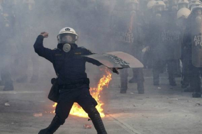 Un policía lanza un objeto contra los manifestantes ante el Parlamento. Foto: YIORGOS KARAHALIS | REUTERS