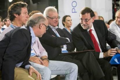 Rajoy habla con Cristóbal Montoro ante el presidente del PP de Murcia, Ramón Luis Valcárcel, y Carlos Floriano, durante la Intermunicipal del PP, este domingo en Murcia.