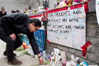 Un hombre coloca una flor en el memorial improvisado a las víctimas del atropello en Toronto.