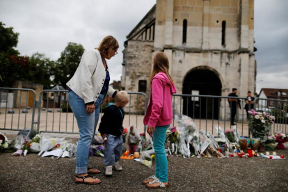 Una madre y sus hijos dejan flores ante la iglesia de Saint-Etienne-du-Rouvray.