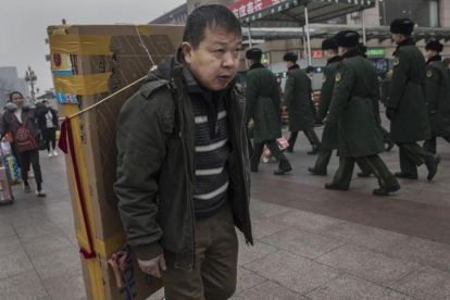 Un hombre llega con un gran televisor en la espalda a la estación central de Pekín, dispuesto a tomar un tren, el 26 de enero.
