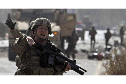 Un soldado norteamericano de la OTAN despeja la zona tras el atentado suicida con coche bomba cometido, hoy, en Kabul.