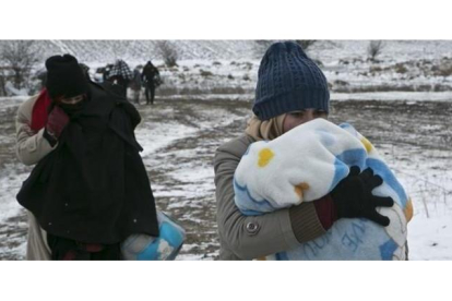 Una mujer migrante protege a su hijo con una manta mientras camina cerca de Miratovac (Serbia), este lunes.