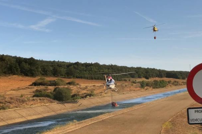 Dos helicópteros recogen agua de un canal para sofocar el incendio en Villapadierna. RAMIRO