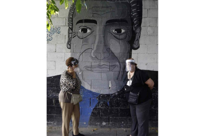 Dos mujeres conversan en la calle ante un graffiti. MIGUEL LEMUS