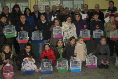 Los ganadores del concurso ornitológico posan con los niños premiados en el certamen de dibujo, que recibieron un canario.