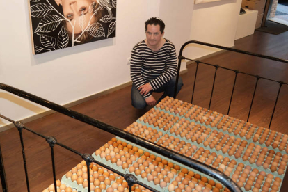 El artista Jean Claude Cubino posa con una monumental cama llena de huevos. CUEVAS