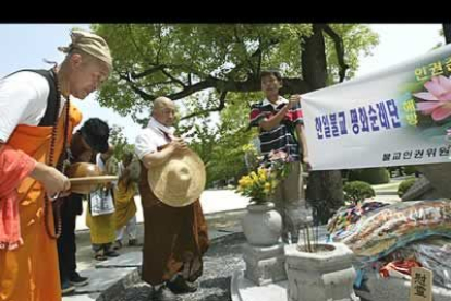 Unos monjes budistas coreanos rezan junto a un grupo de fieles frente al monumento dedicado a las víctimas coreanas de la explosión de la bomba atómica.