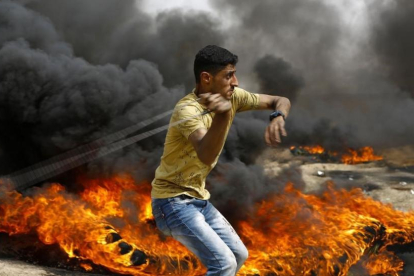 Un palestino se dispone a lanzar piedras entre los neumáticos incendiados contra las tropas israelís, en las protestas junto a la frontera de la Franja de Gaza, el 20 de abril.