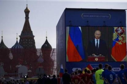 Un grupo de funcionarios y jugadores de fútbol miran el discurso televisado del presidente ruso, Vladimir Putin, en la Plaza Roja de Moscú, este viernes.