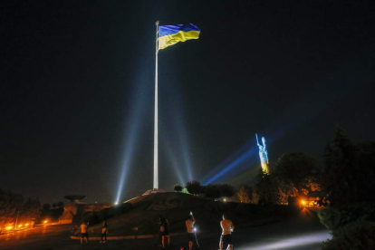 Una bandera y el monumento a la Patria, iluminado con los colores de Ucrania, en Kiev. SERGEY DOLZHENKO