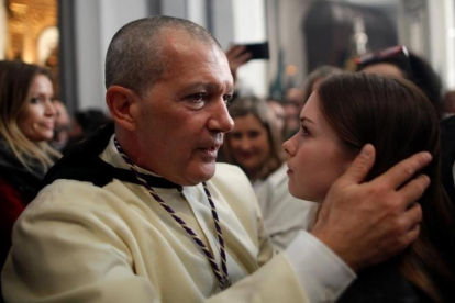 Antonio Banderas abraza a su hija, Estela del Carmen, antes de salir como penitente de Las Lágrimas. A la izquierda, la novia del actor, Nicole Kimpel.