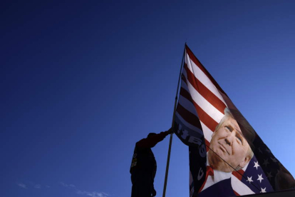 Un americano arría una bandera con la efigie de Donald Trump. WILL OLIVER