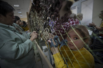 Una niña ucraniana ayuda a colocar una verja de camuflage para el ejército de UCrania. MARIA SENOVILLA