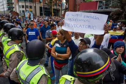 Un grupo de personas protesta frente a miembros de la Policía Nacional Bolivariana (PNB) en la ciudad de Caracas (Venezuela).
