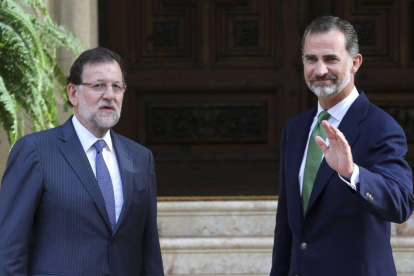 El rey Felipe VI saluda junto al presidente del Gobierno, Mariano Rajoy (i), hoy al Palacio de Marivent, en Palma de Mallorca, donde se han reunido en el único despacho que ambos celebran este verano en la residencia de verano de la familia real.