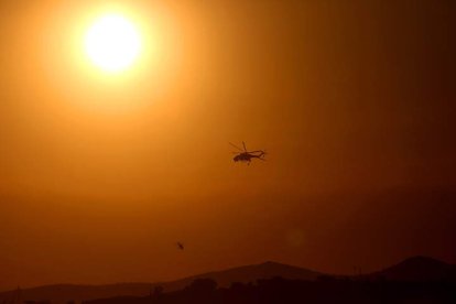 Un sol abrasador con un helicópetero que combate un fuego en el Mediterráneo. ORESTIS PANAGIOTOU