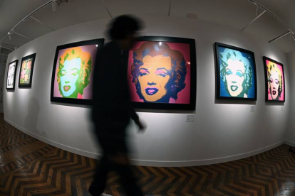 Un visitante pasa junta a varios retratos de Marilyn Monroe, obra del artista estadounidense Andy Warhol, y que forman parte de la muestra 