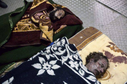 Fotografía de los cuerpos muertos del ex líder libio, Muammar Gaddafi (d), y su hijo Mutassim Gaddafi .