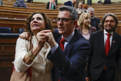 Los ministros en funciones Félix Bolaños (c) y María Jesús Montero (i) se felicitan después de que el presidente del Gobierno en funciones, Pedro Sánchez, haya sido reelegido. HIDALGO