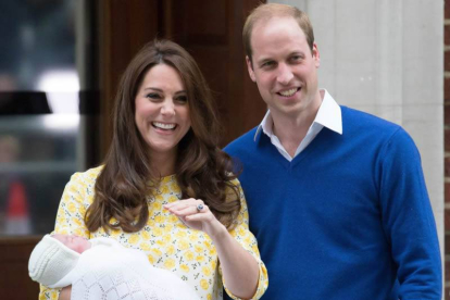 El príncipe William junto a su mujer, Kate Middleton, sonríen felices al abandonar el hospital llevando en brazos a la princesa recién nacida.